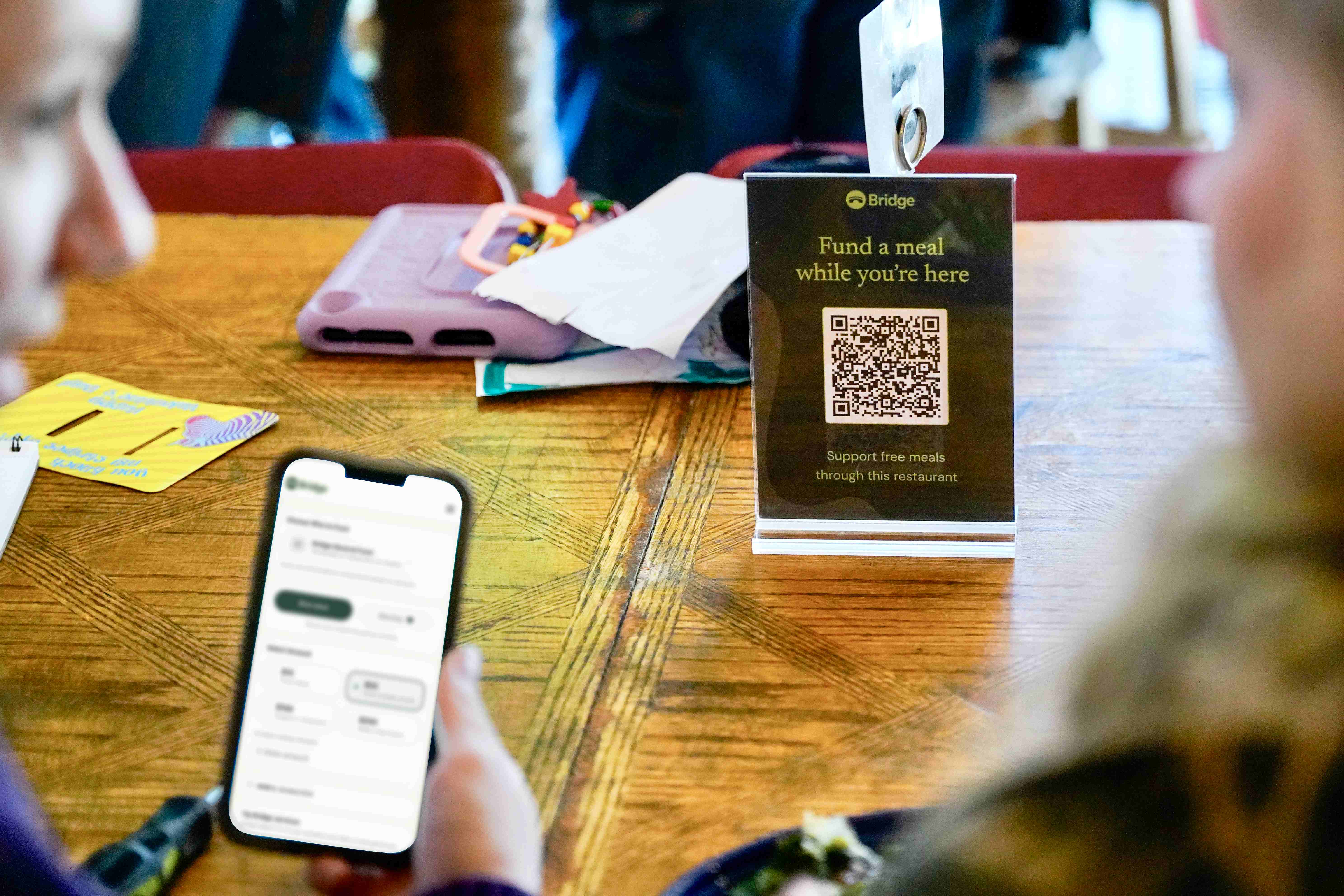 A Bridge Meals QR code table tent at a restaurant for funding meals